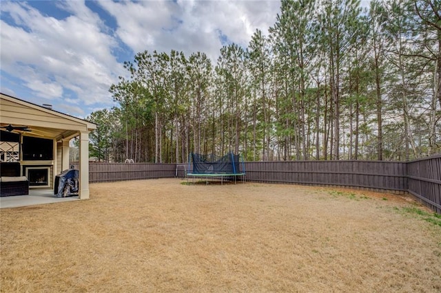 view of yard featuring a patio, a trampoline, a fenced backyard, and a ceiling fan