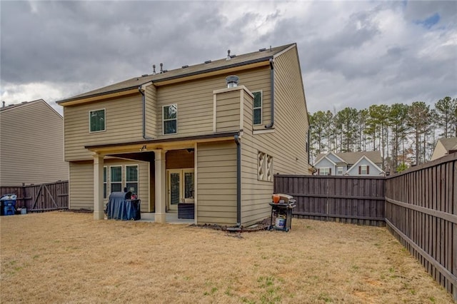 rear view of property featuring a patio, a lawn, and a fenced backyard