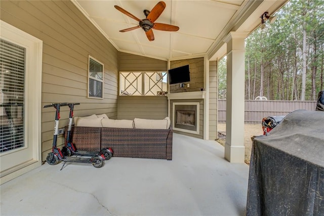 view of patio / terrace featuring an outdoor living space with a fireplace, fence, and a ceiling fan