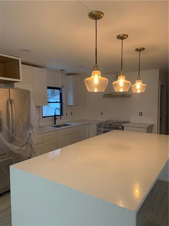 kitchen with white cabinetry, stainless steel appliances, decorative light fixtures, and sink