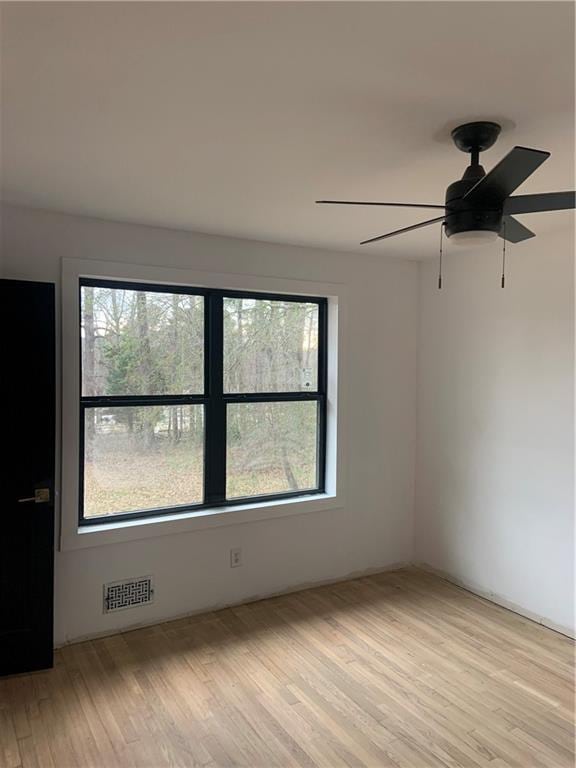 empty room featuring ceiling fan, a healthy amount of sunlight, and light wood-type flooring