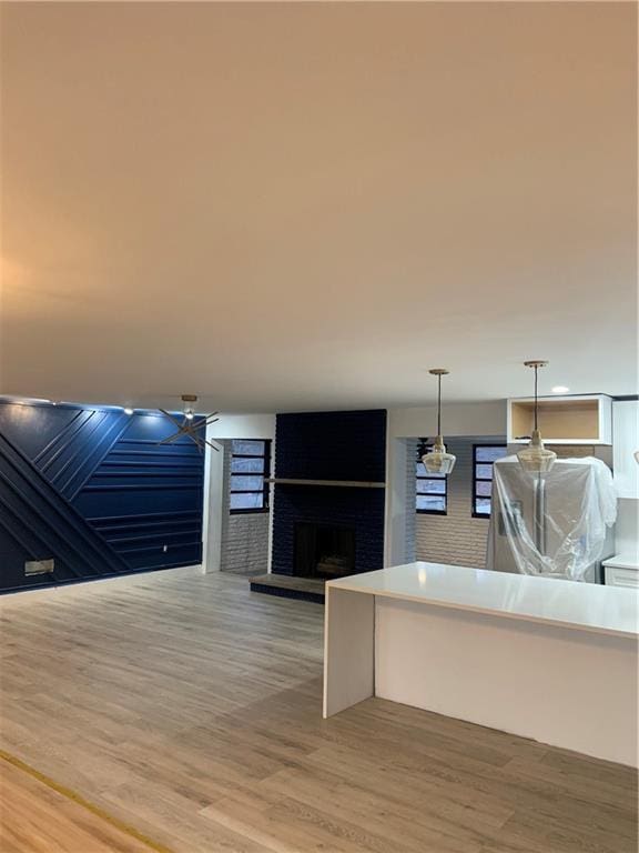 kitchen with pendant lighting, hardwood / wood-style floors, and a brick fireplace