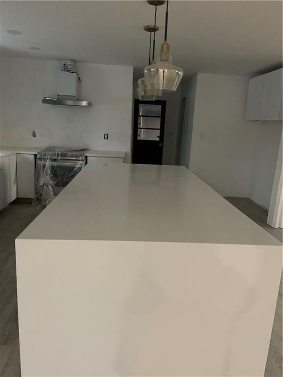 kitchen featuring a kitchen island, pendant lighting, range hood, white cabinetry, and stainless steel range with electric stovetop