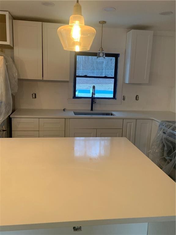 kitchen featuring sink, pendant lighting, and white cabinets