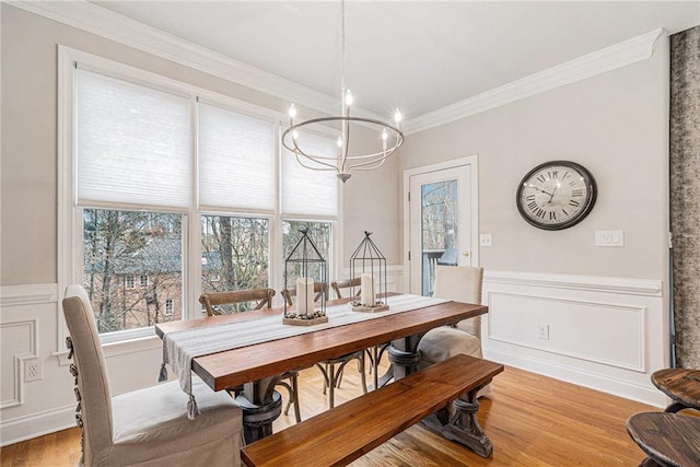 dining space with ornamental molding, a notable chandelier, and light hardwood / wood-style floors