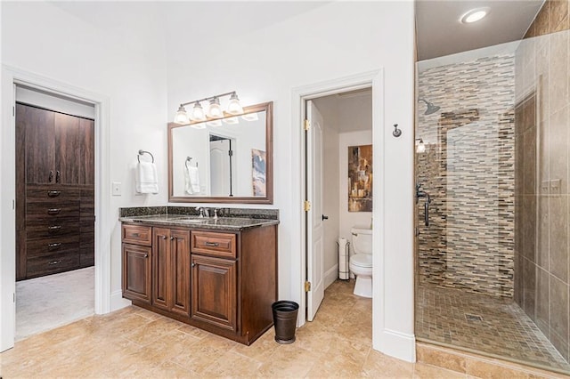 bathroom with tiled shower, vanity, and toilet