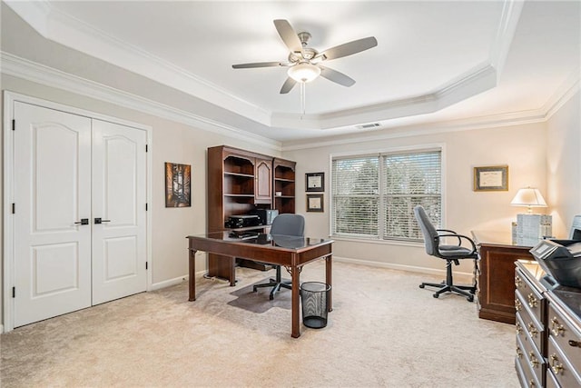 carpeted office space featuring ceiling fan, ornamental molding, and a raised ceiling