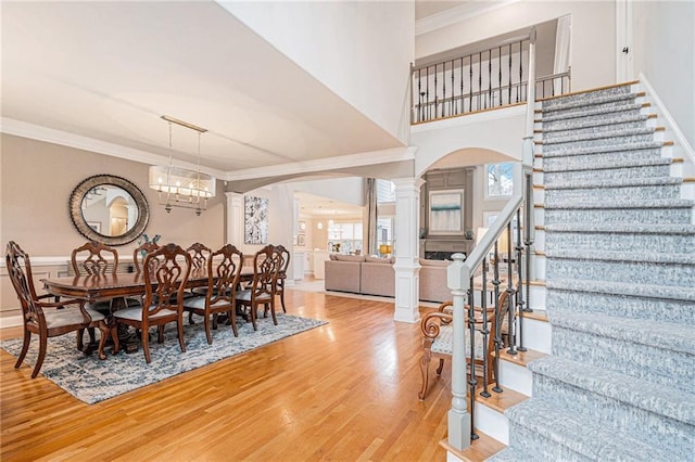 dining area featuring hardwood / wood-style flooring, crown molding, decorative columns, and a notable chandelier