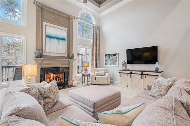 living room with a premium fireplace, a towering ceiling, ornamental molding, and a healthy amount of sunlight