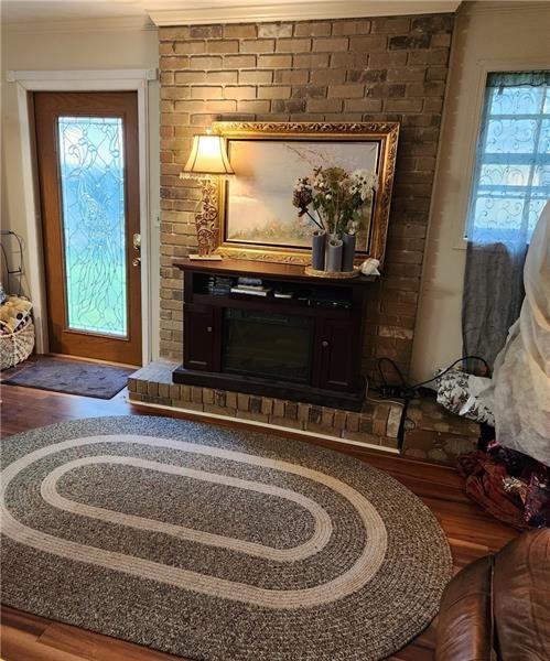 living area with crown molding, wood finished floors, and plenty of natural light
