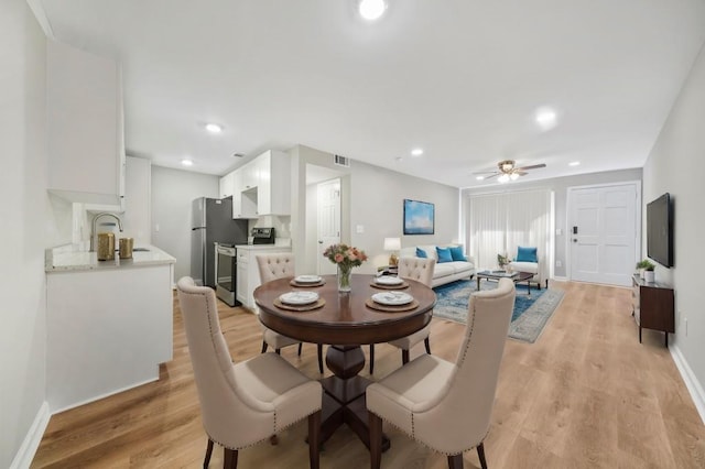 dining area with sink, ceiling fan, and light wood-type flooring