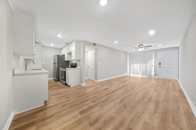 unfurnished living room featuring sink, ceiling fan, and light hardwood / wood-style flooring