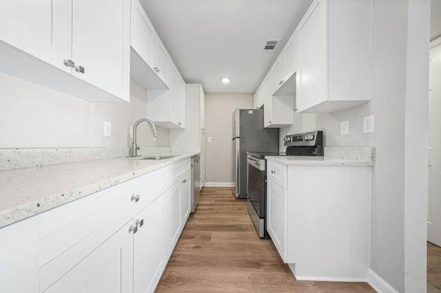 kitchen with appliances with stainless steel finishes, light stone countertops, and white cabinets