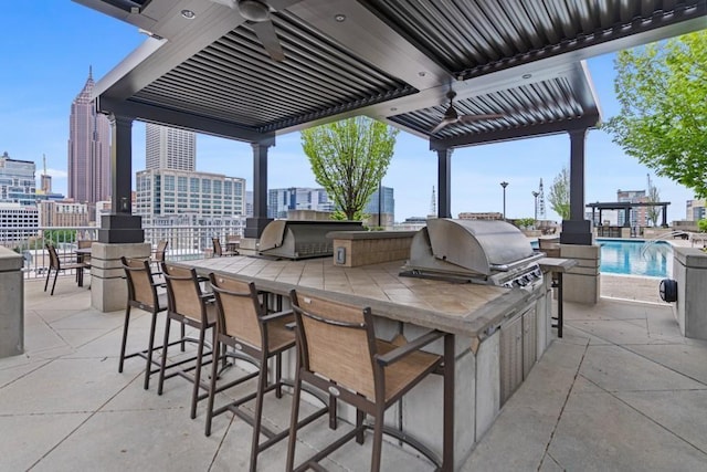 view of patio / terrace featuring grilling area, a view of city, exterior kitchen, and outdoor wet bar