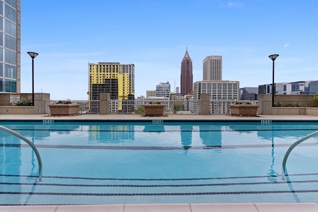 view of swimming pool with a city view and fence