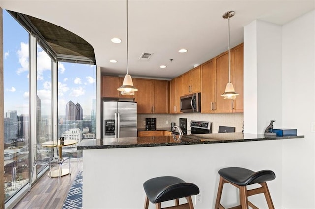 kitchen featuring visible vents, dark stone countertops, dark wood-style floors, appliances with stainless steel finishes, and a peninsula