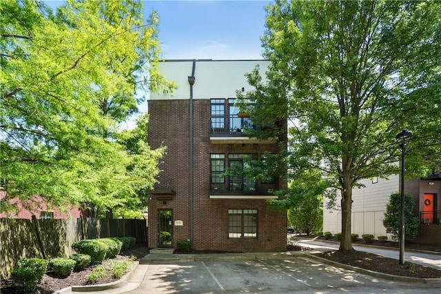 1300 Dekalb Ave NE Unit 731, Atlanta, GA 30307 - view of front of property with brick siding, fence, a balcony, and uncovered parking