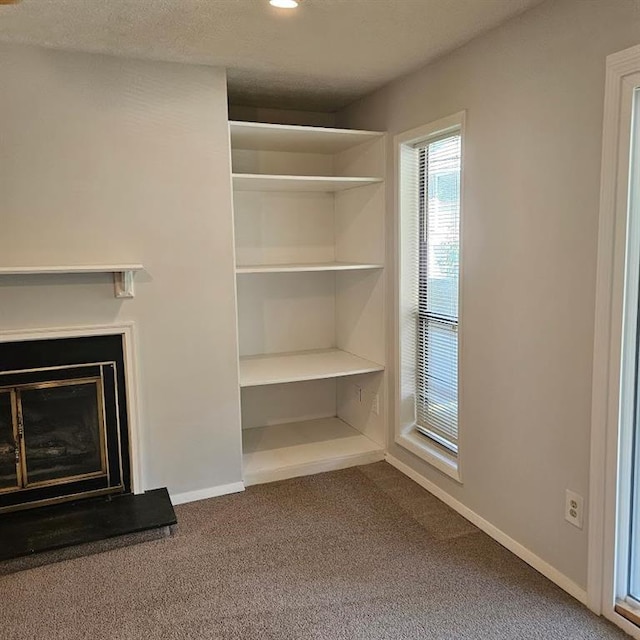 unfurnished living room featuring baseboards, a glass covered fireplace, carpet, a textured ceiling, and recessed lighting