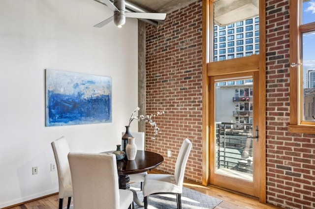 dining area featuring brick wall, ceiling fan, and light hardwood / wood-style floors