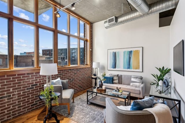 living room with brick wall and hardwood / wood-style floors