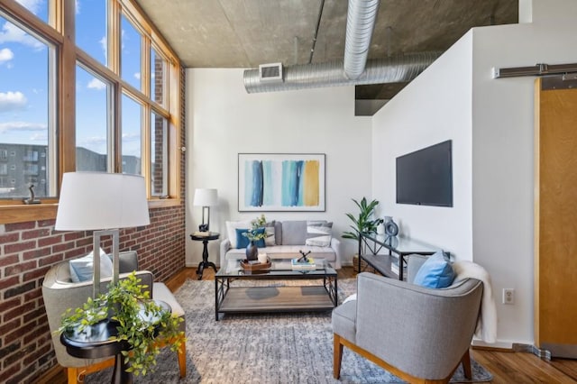 living room with brick wall, wood-type flooring, and a barn door