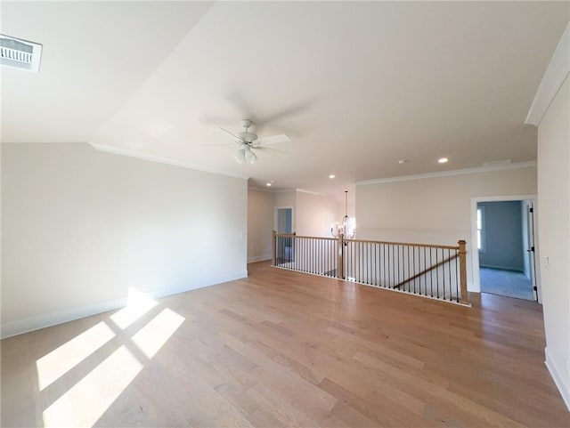 spare room featuring lofted ceiling, ceiling fan with notable chandelier, light hardwood / wood-style flooring, and ornamental molding