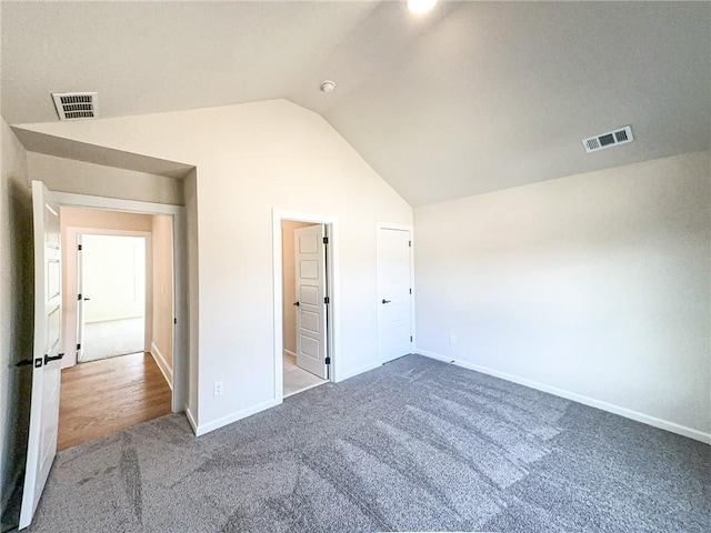 unfurnished bedroom with carpet flooring and lofted ceiling