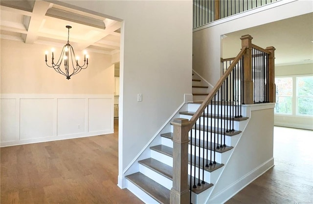 staircase with beamed ceiling, wood-type flooring, coffered ceiling, and a notable chandelier