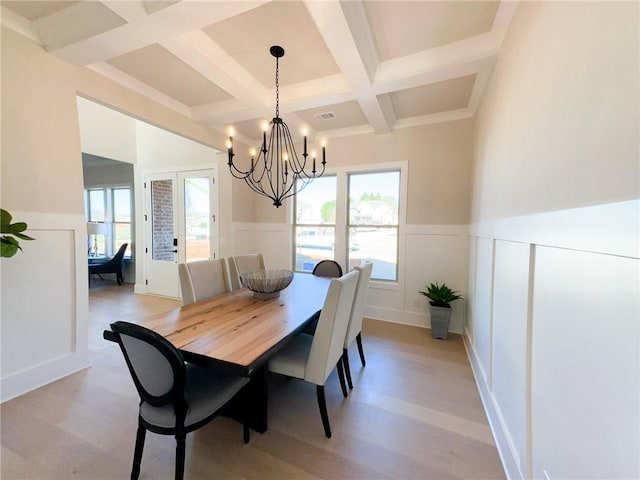 dining area featuring beam ceiling, light hardwood / wood-style floors, coffered ceiling, and a notable chandelier