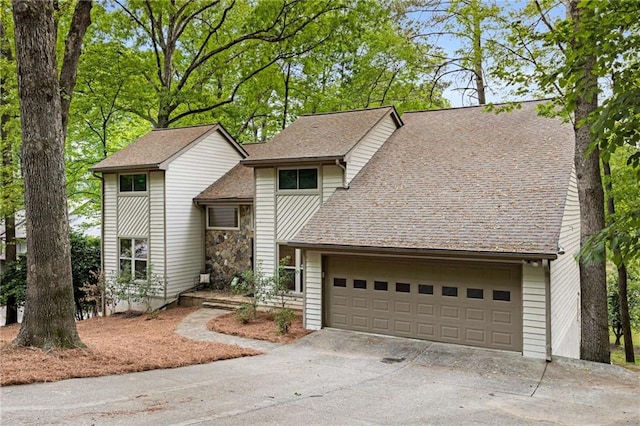bi-level home with a shingled roof, an attached garage, and aphalt driveway