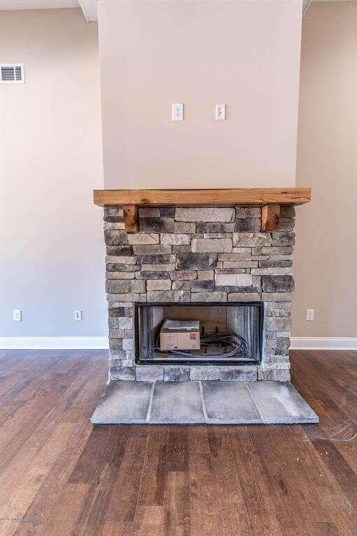 room details with baseboards, a fireplace, visible vents, and wood finished floors