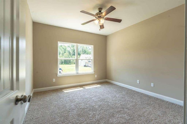 carpeted spare room with ceiling fan and baseboards