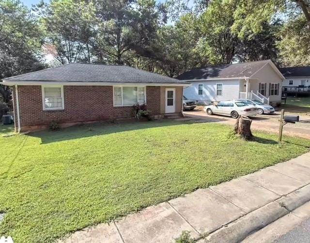 ranch-style home featuring brick siding and a front lawn