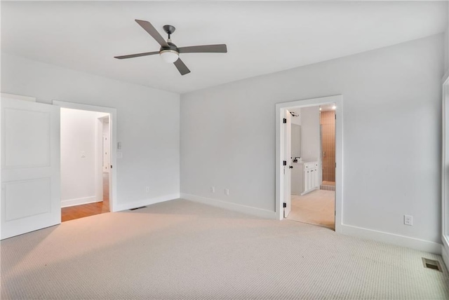 unfurnished bedroom featuring light carpet, connected bathroom, and ceiling fan