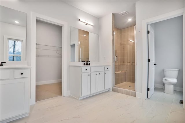 bathroom featuring vanity, a shower with shower door, and toilet