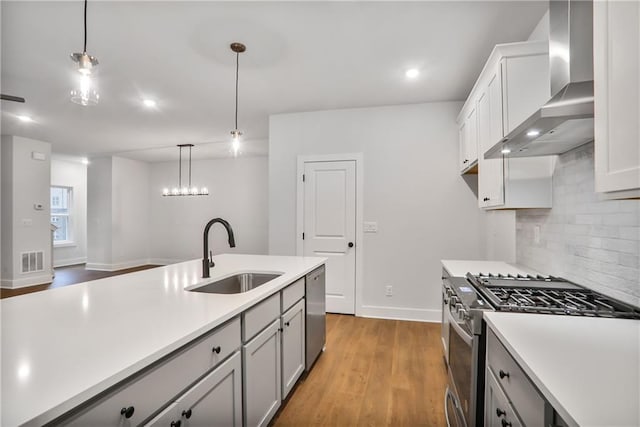 kitchen featuring appliances with stainless steel finishes, tasteful backsplash, sink, hanging light fixtures, and wall chimney range hood