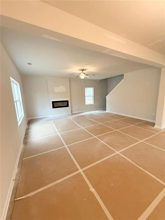 5518 Legacy Trl, Douglasville, GA 30135 - unfurnished living room featuring baseboards, a glass covered fireplace, light tile patterned flooring, and ceiling fan