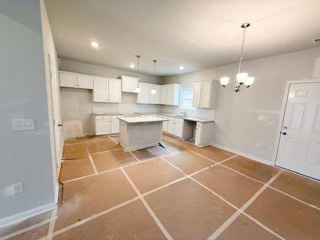 5518 Legacy Trl, Douglasville, GA 30135 - kitchen with a center island, a chandelier, white cabinetry, baseboards, and pendant lighting