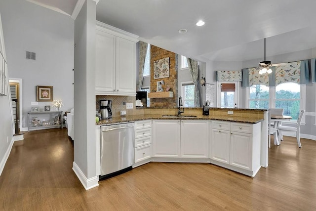 kitchen with kitchen peninsula, white cabinetry, stainless steel dishwasher, and sink