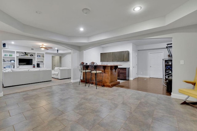 kitchen with a kitchen bar, built in shelves, and ceiling fan