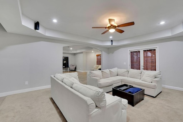 carpeted living room featuring ceiling fan and a tray ceiling