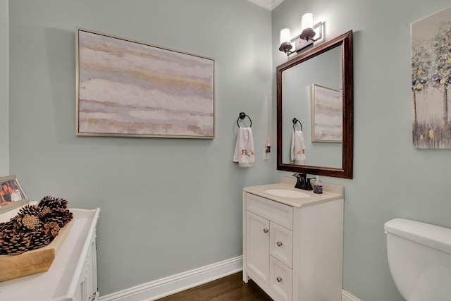 bathroom featuring vanity, toilet, wood-type flooring, and crown molding