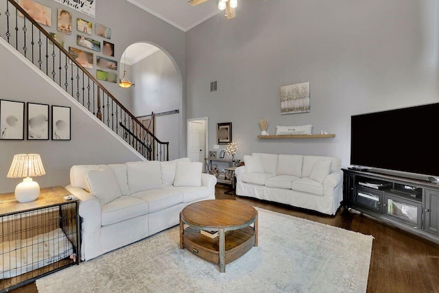 living room with ceiling fan, dark hardwood / wood-style flooring, a towering ceiling, and ornamental molding