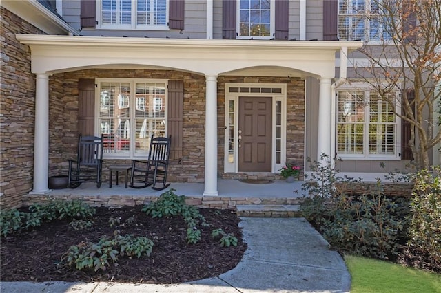 view of exterior entry featuring stone siding and covered porch