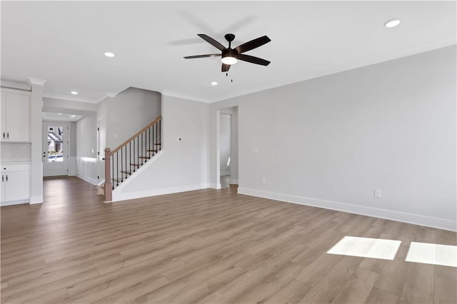 unfurnished living room with crown molding, light wood-type flooring, a ceiling fan, recessed lighting, and stairway