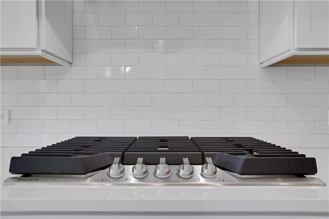 interior details featuring tasteful backsplash, light countertops, white cabinetry, and stainless steel gas cooktop