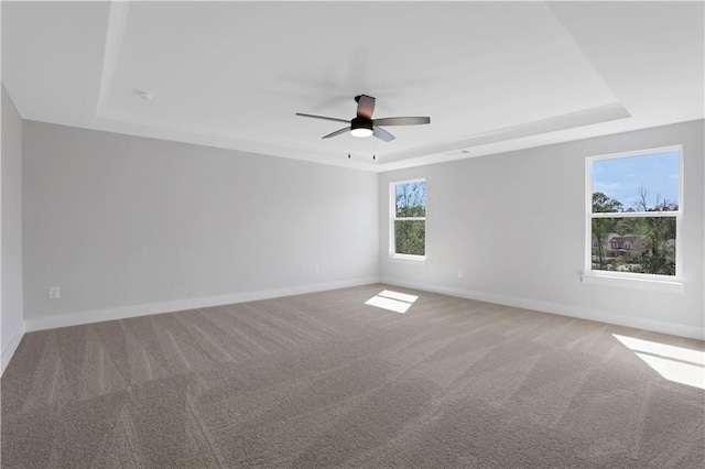 unfurnished room featuring baseboards, a tray ceiling, and a ceiling fan