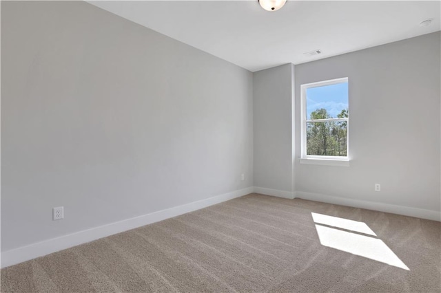 empty room featuring carpet flooring, visible vents, and baseboards