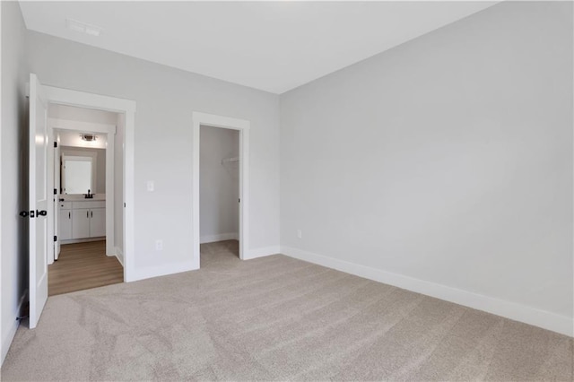 unfurnished bedroom with a spacious closet, carpet flooring, baseboards, and a closet