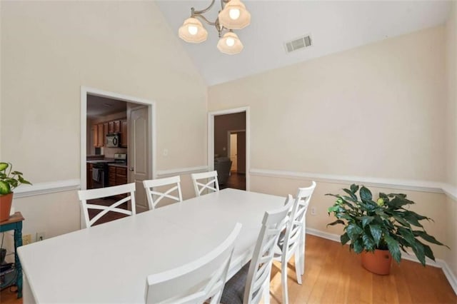 dining space featuring a chandelier, wood finished floors, high vaulted ceiling, and baseboards